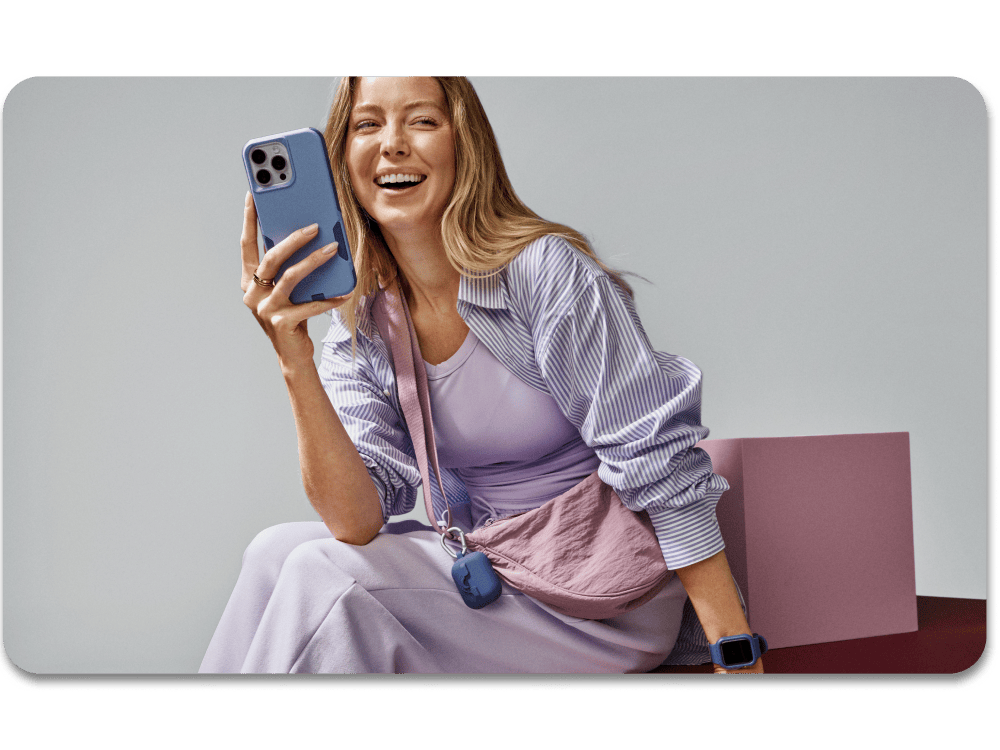 Woman laughing holding an iPhone 16 with a blue protective case